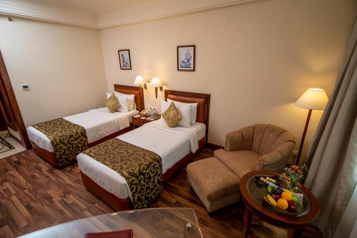 a hotel room with two beds and a chair at The Accord Metropolitan in Chennai