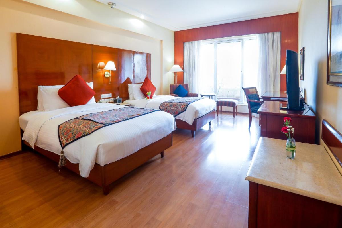 a hotel room with two beds and a television at The Lalit Mumbai in Mumbai