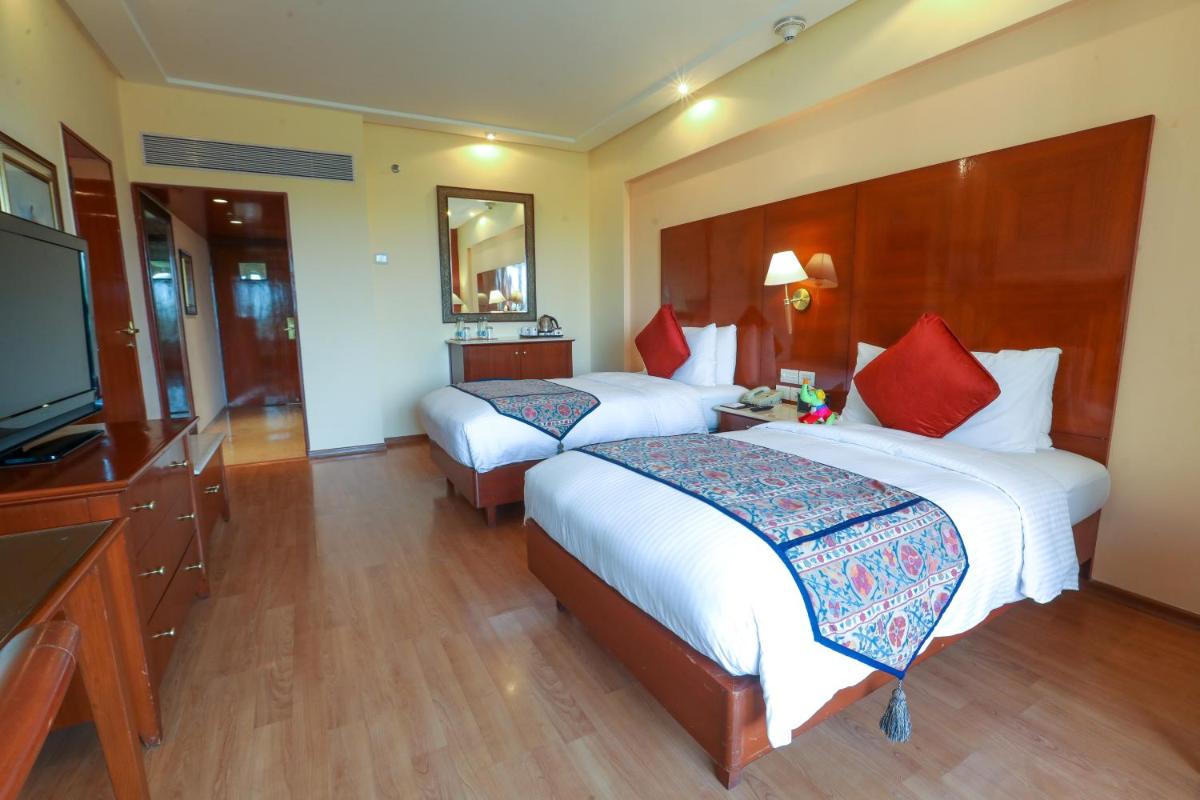 a hotel room with two beds and a flat screen tv at The Lalit Mumbai in Mumbai