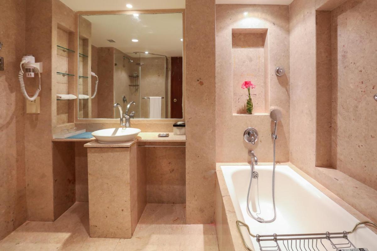 a bathroom with a bath tub and a sink at The Lalit Mumbai in Mumbai