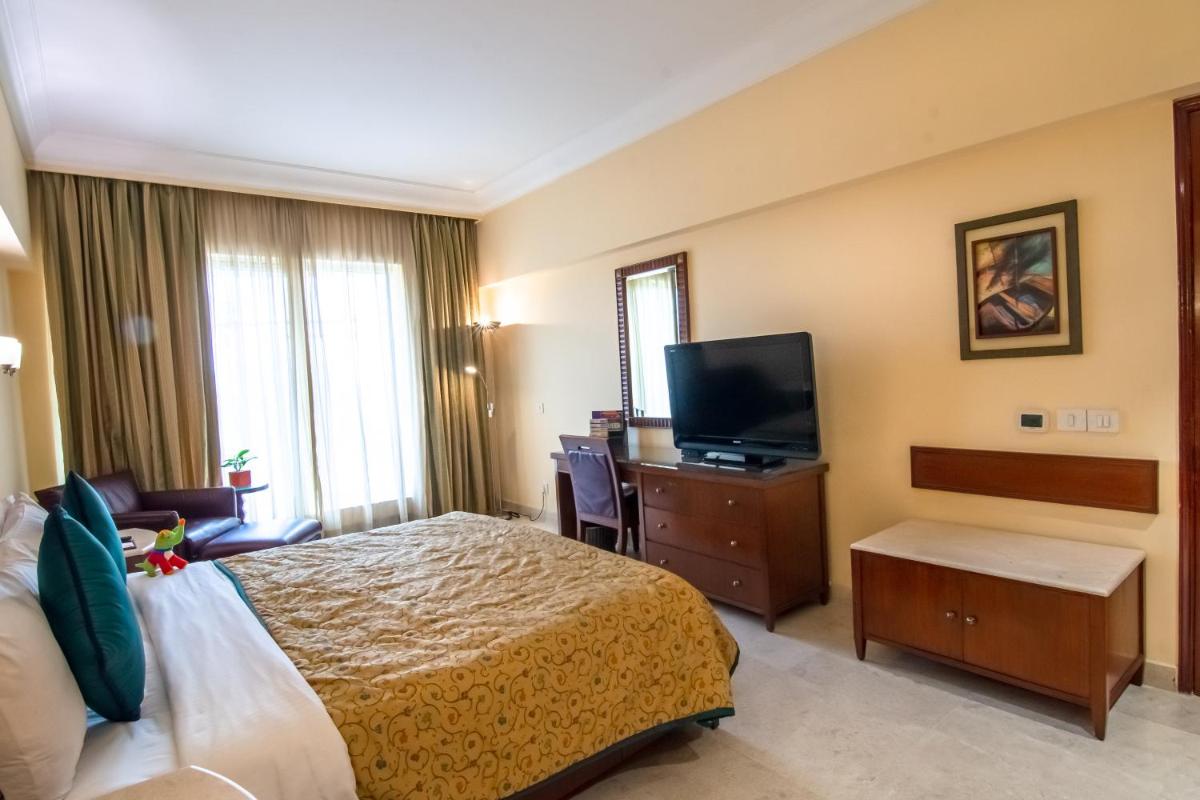 a hotel room with a bed and a flat screen tv at The Lalit Mumbai in Mumbai