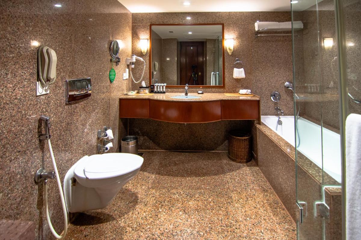 a bathroom with a toilet and a sink and a shower at The Lalit Mumbai in Mumbai
