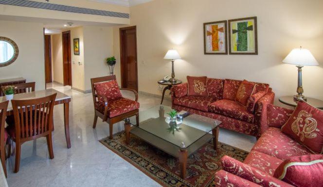 a living room with red couches and a table at The Lalit Mumbai in Mumbai