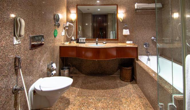 a bathroom with a tub and a toilet and a sink at The Lalit Mumbai in Mumbai