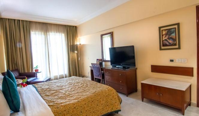 a hotel room with a bed and a flat screen tv at The Lalit Mumbai in Mumbai