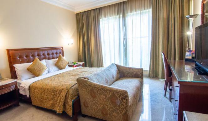 a hotel room with a bed and a couch at The Lalit Mumbai in Mumbai