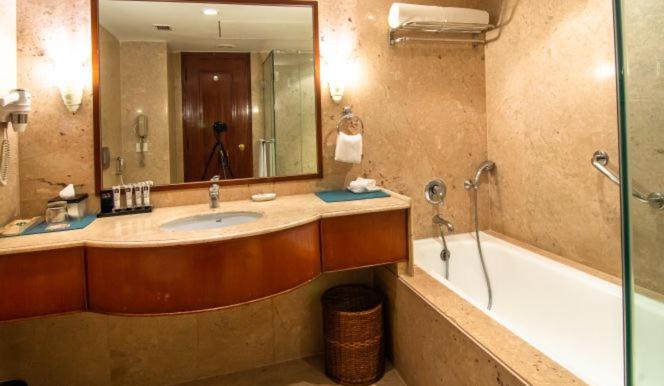 a bathroom with a sink and a tub and a mirror at The Lalit Mumbai in Mumbai