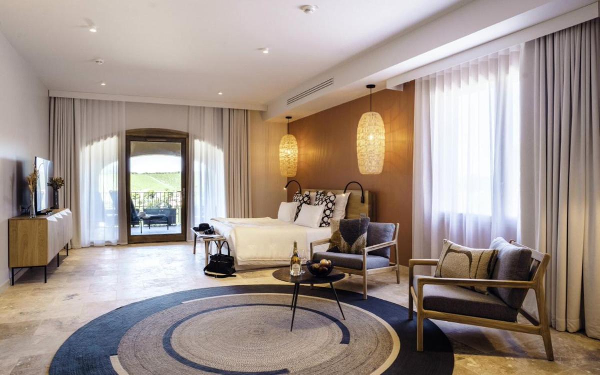 une chambre d'hôtel avec un lit, une table et des chaises dans l'établissement Château L'Hospitalet Wine Resort Beach & Spa, à Narbonne