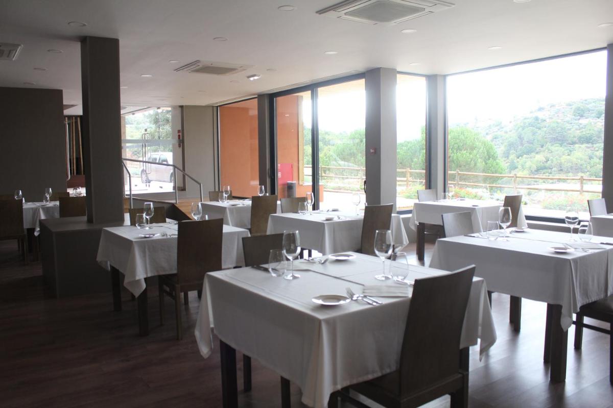 uma sala de jantar com mesas e cadeiras brancas e janelas em Douro Cister Hotel Resort em Ucanha