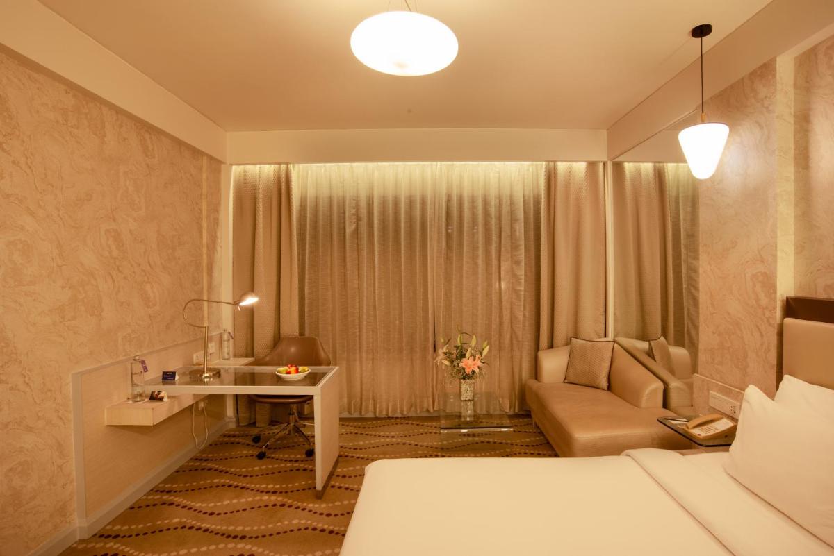 a hotel room with a bed and a desk and a couch at Radisson Blu Bengaluru Outer Ring Road in Bengaluru