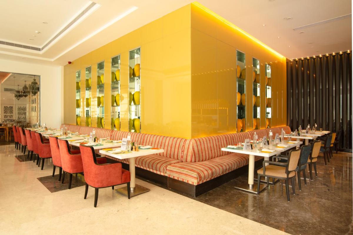 a restaurant with long tables and red chairs at Radisson Blu Bengaluru Outer Ring Road in Bengaluru