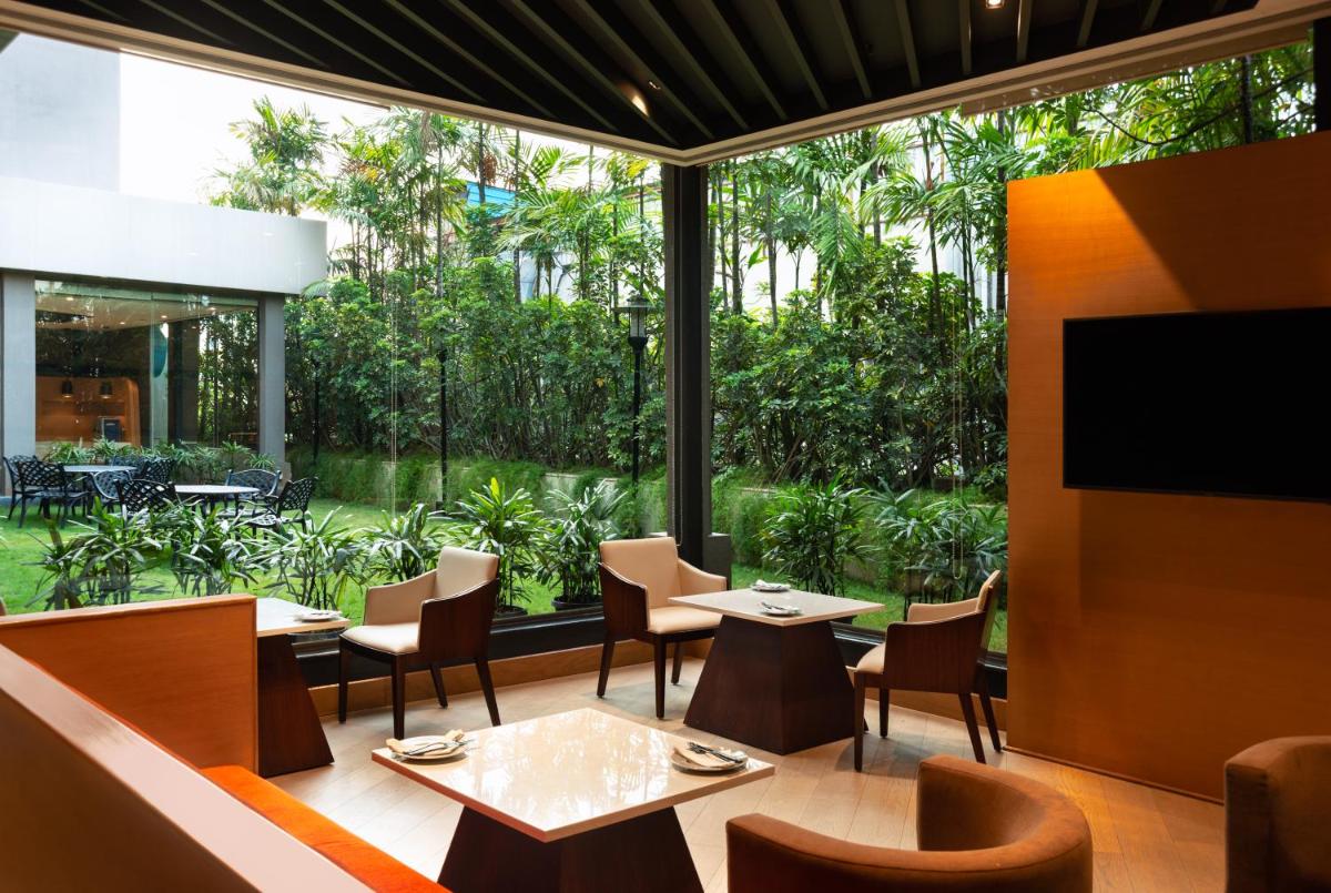 a restaurant with tables and chairs and a large window at Radisson Blu Bengaluru Outer Ring Road in Bengaluru