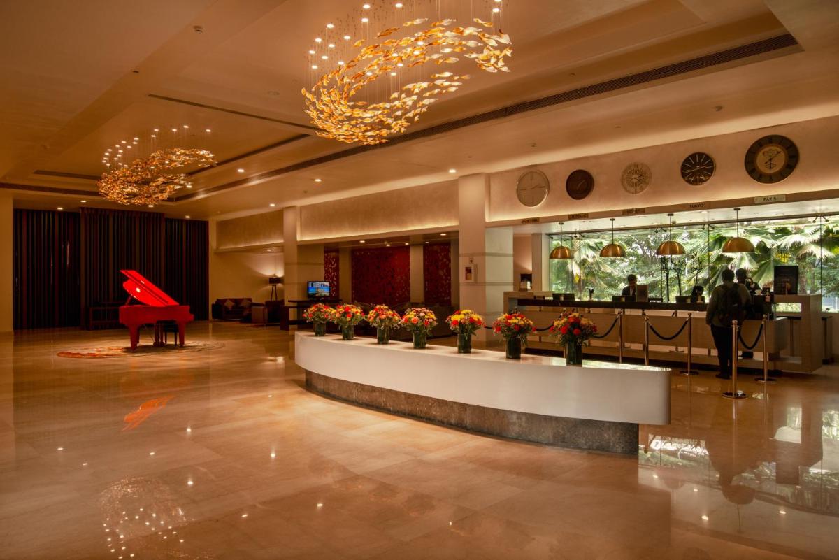 a lobby with a piano and flowers in a room at Radisson Blu Bengaluru Outer Ring Road in Bengaluru