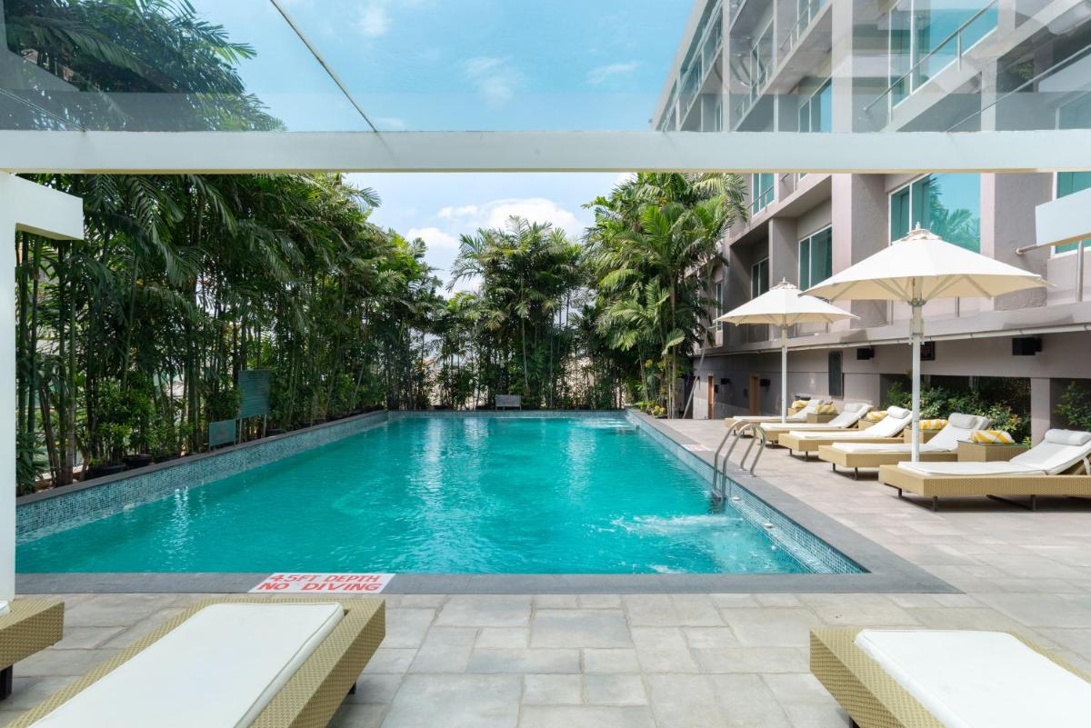 a swimming pool with lounge chairs and a building at Radisson Blu Bengaluru Outer Ring Road in Bengaluru