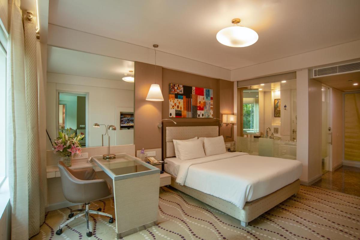 a hotel room with a bed and a desk and a desk at Radisson Blu Bengaluru Outer Ring Road in Bengaluru