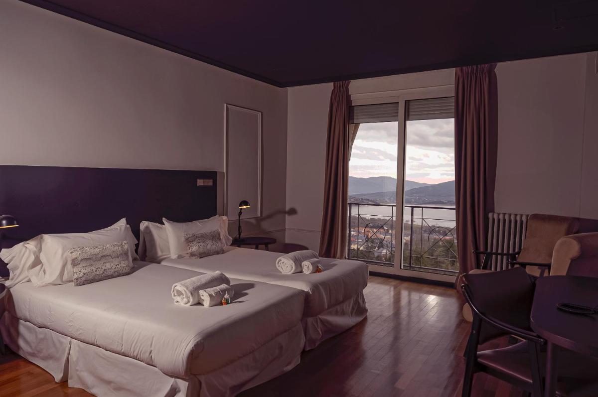 Una habitación de hotel con dos camas y una gran ventana. en Hotel Hita "Nature Experience" for all, en Navacerrada 180 fotos más