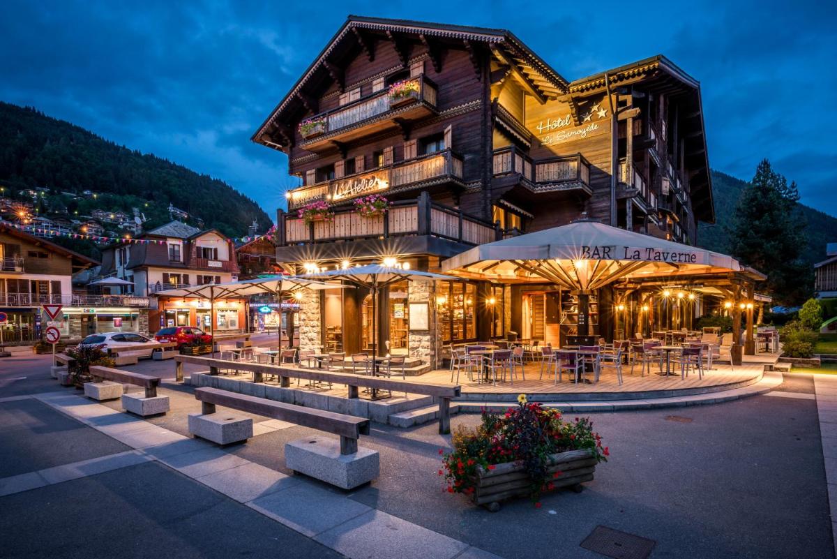 un bâtiment avec des tables et des chaises devant lui dans l'établissement Hotel Le Samoyede, à Morzine