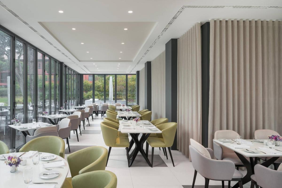 uma sala de jantar com mesas, cadeiras e janelas em Sheraton Cascais Resort - Hotel & Residences em Cascais