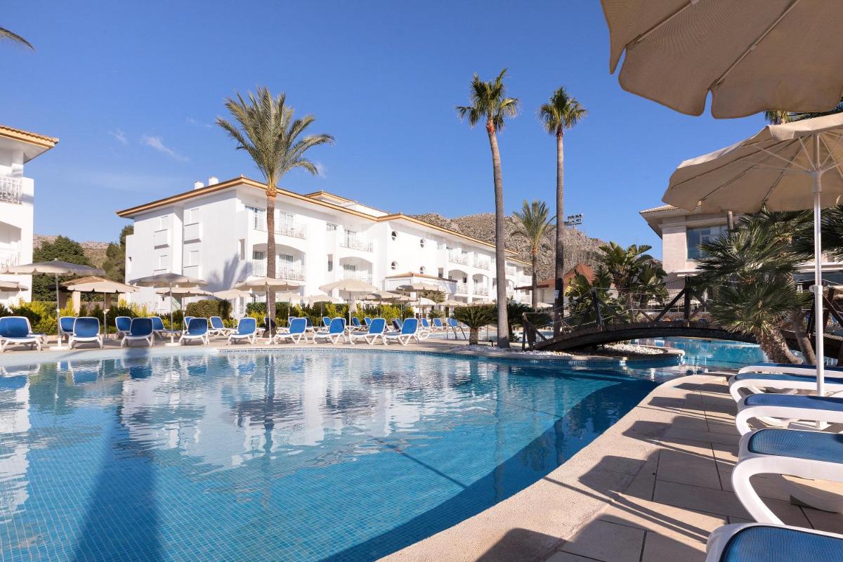 Una piscina en un hotel con sillas y palmeras. en Mar Hotels Playa Mar & Spa, en Puerto Pollensa