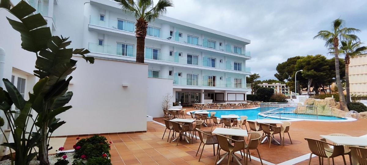 un hotel con mesas y sillas junto a una piscina en Hotel Capricho, en Cala Ratjada