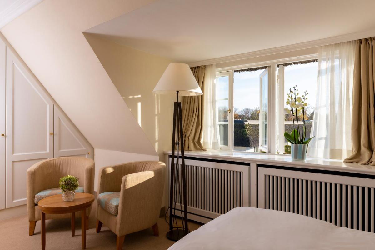 Zimmer mit einem Bett, 2 Stühlen und einem Fenster in der Unterkunft Benen-Diken-Hof in Keitum Zimmer mit einem Bett, 2 Stühlen und einem Fenster in der Unterkunft Benen-Diken-Hof in Keitum