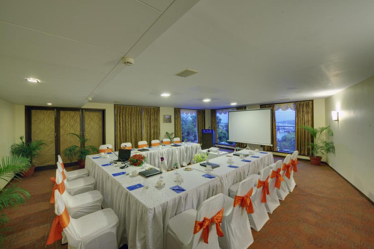 a conference room with tables and chairs and a screen at The Crown Goa in Panaji