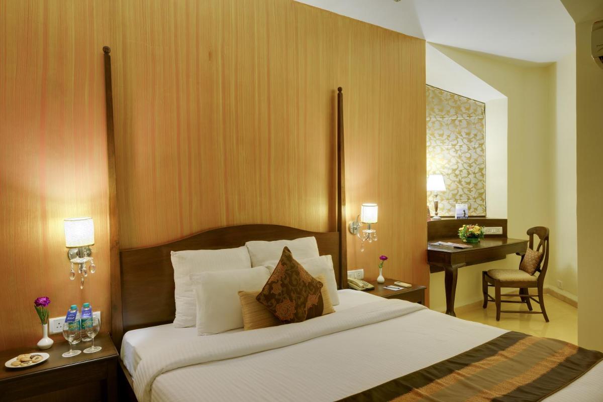 a hotel room with a large bed and a desk at The Crown Goa in Panaji