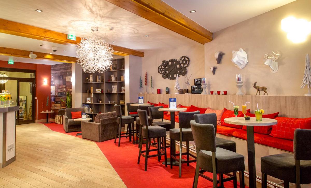 un restaurant avec des meubles rouges, des tables et des chaises dans l'établissement SOWELL HOTELS Le Parc & Spa, à Briançon