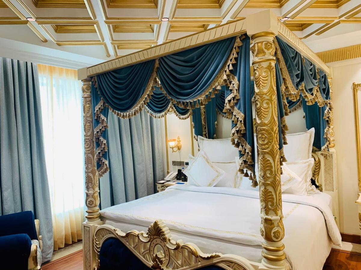 a bedroom with a four poster bed with blue curtains at The Accord Metropolitan in Chennai