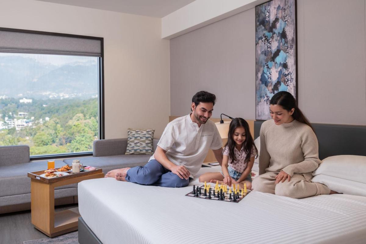 a family sitting on a bed playing chess at Fairfield by Marriott Dehradun in Dehradun