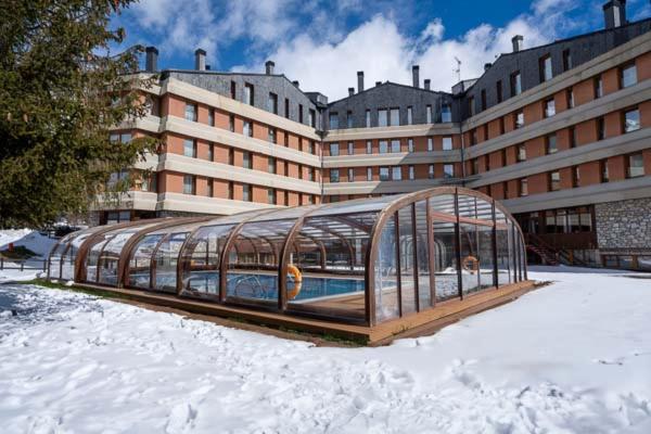 un invernadero de cristal en la nieve frente a un edificio en Hotel Montarto, en Baqueira Beret