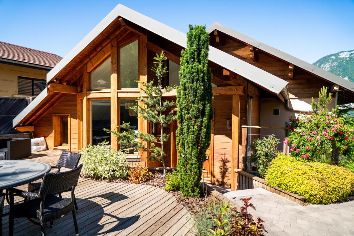 une maison avec une terrasse avec une table et des chaises dans l'établissement Les Trésoms Lake and Spa Resort, à Annecy