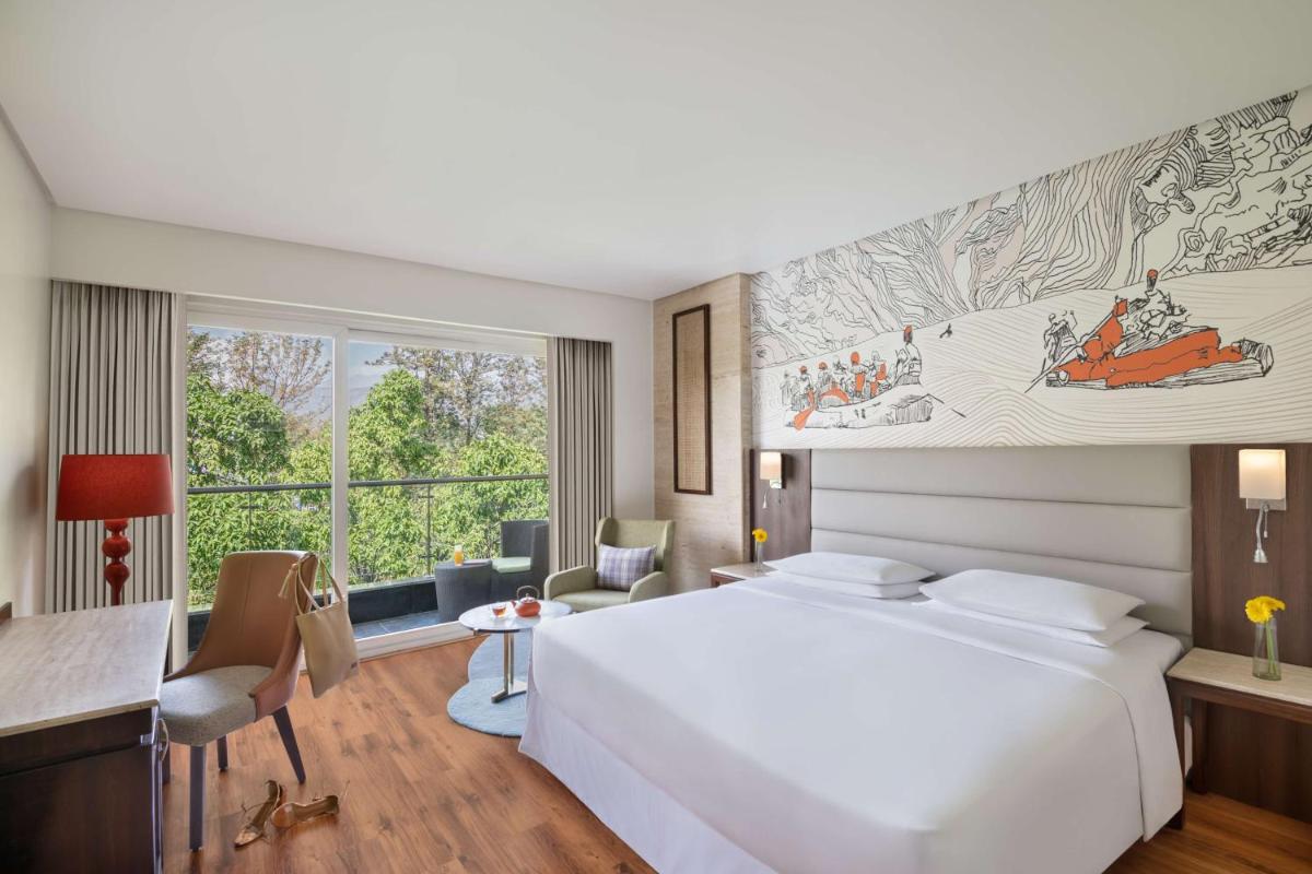a bedroom with a large white bed and a desk at Hyatt Centric Rajpur Road Dehradun in Dehradun