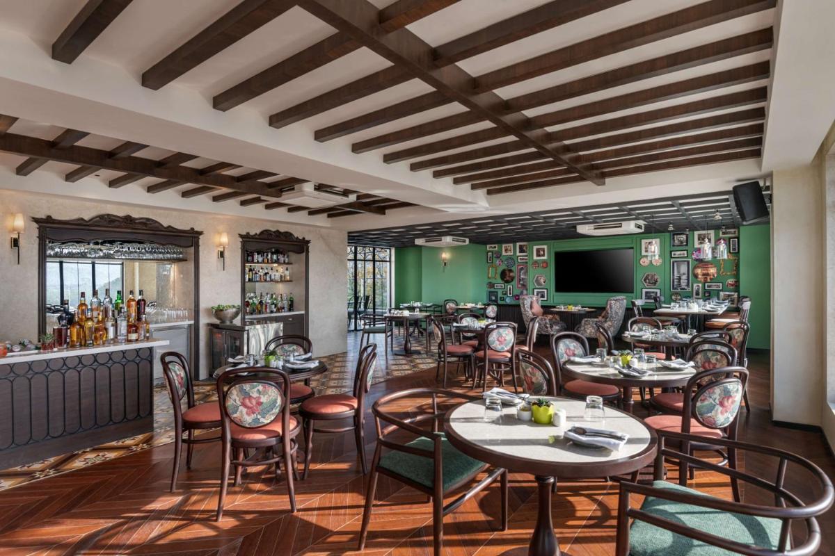 a restaurant with tables and chairs and a bar at Hyatt Centric Rajpur Road Dehradun in Dehradun