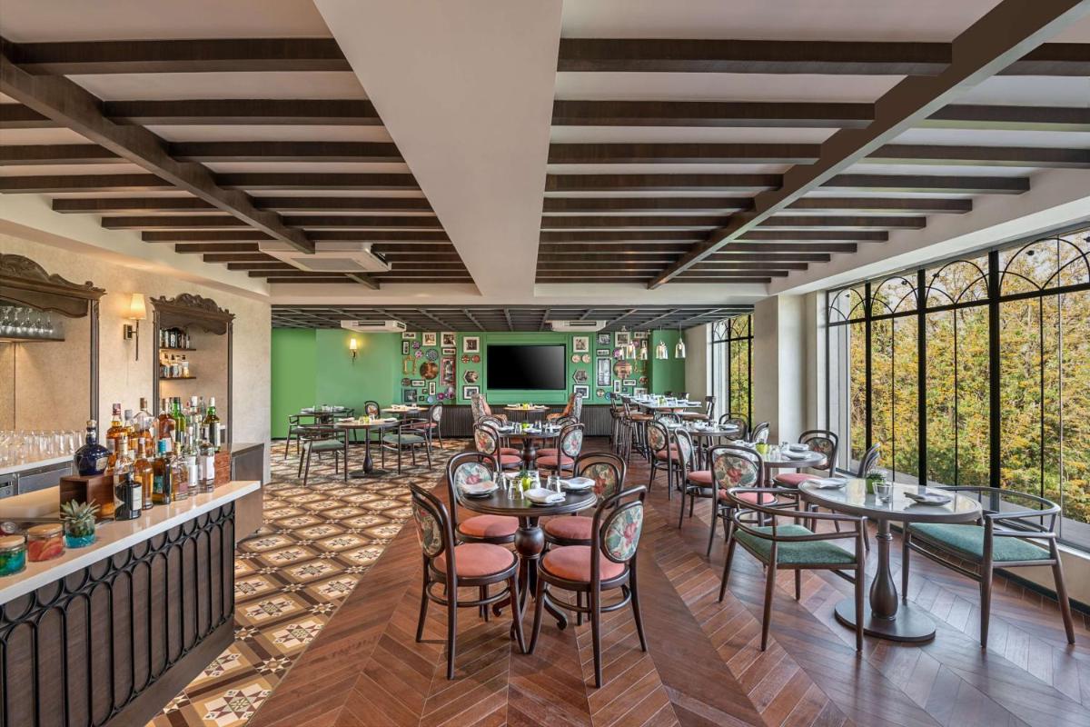 a restaurant with tables and chairs and a bar at Hyatt Centric Rajpur Road Dehradun in Dehradun