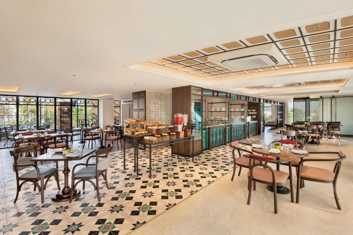 a restaurant with tables and chairs and windows at Hyatt Centric Rajpur Road Dehradun in Dehradun