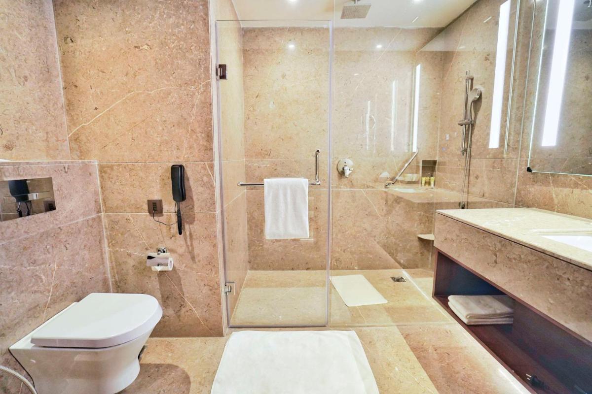 a bathroom with a shower and a toilet and a sink at Hyatt Centric Rajpur Road Dehradun in Dehradun