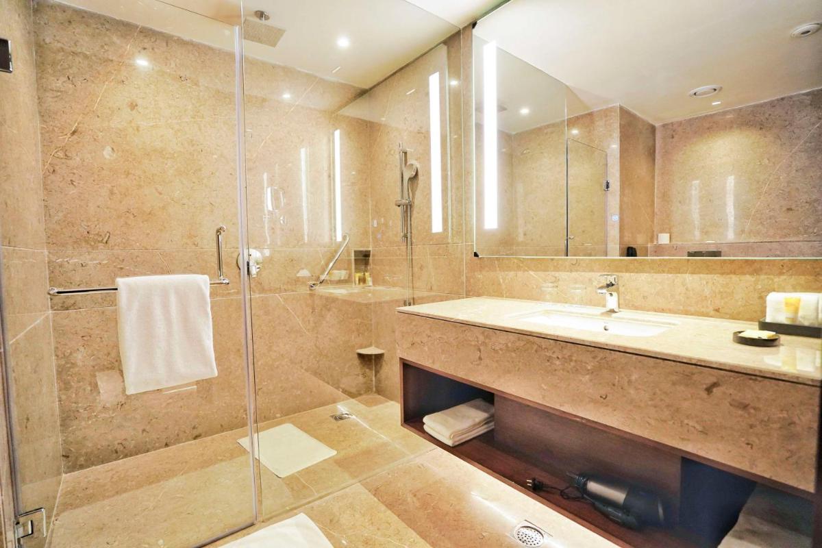 a bathroom with a sink and a glass shower at Hyatt Centric Rajpur Road Dehradun in Dehradun