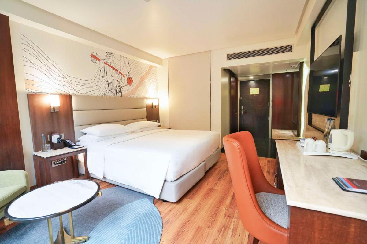 a hotel room with a bed and a table and chairs at Hyatt Centric Rajpur Road Dehradun in Dehradun