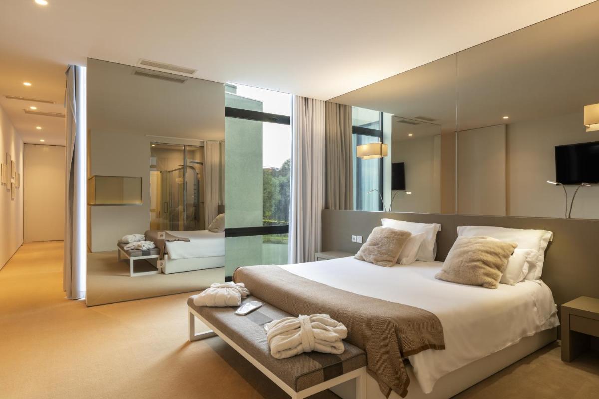 um quarto com uma cama grande e um espelho grande em Tempus Hotel & Spa em Ponte da Barca um quarto com uma cama grande e um espelho grande em Tempus Hotel & Spa em Ponte da Barca