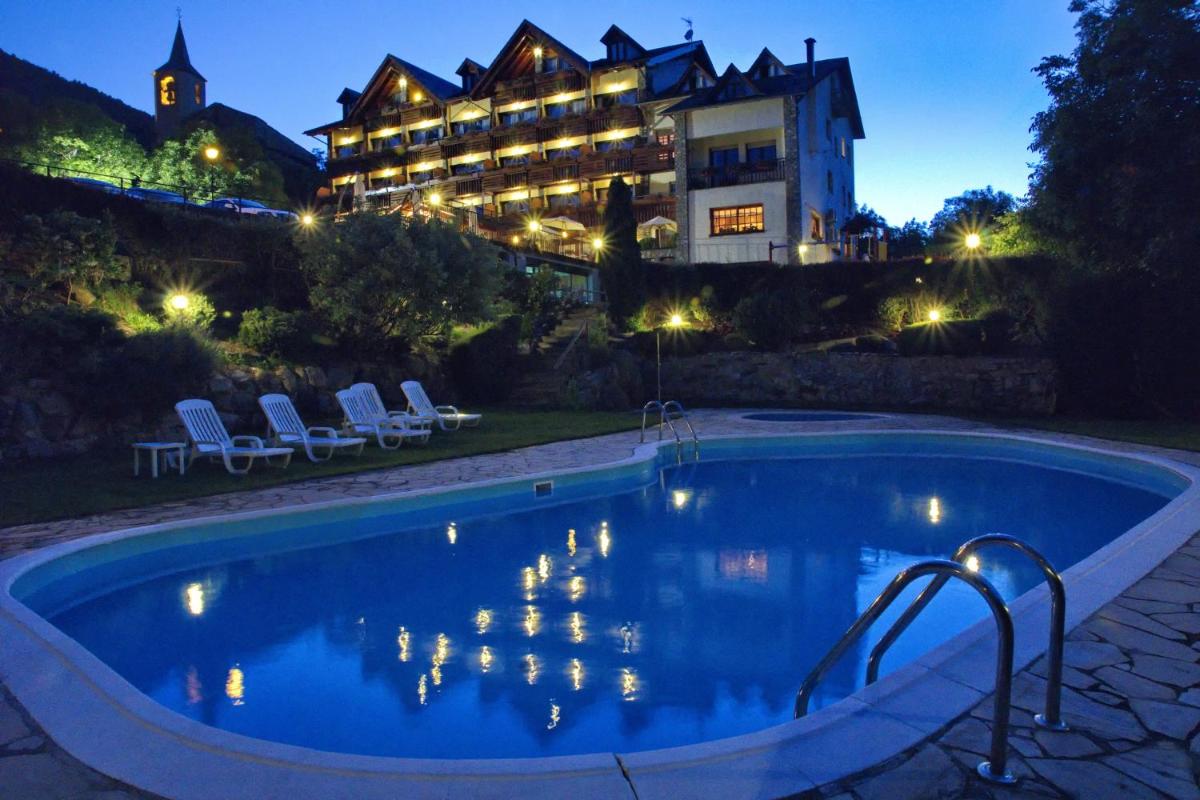 Una piscina frente a un hotel por la noche. en Hotel La Morera, en Valencia de Aneu