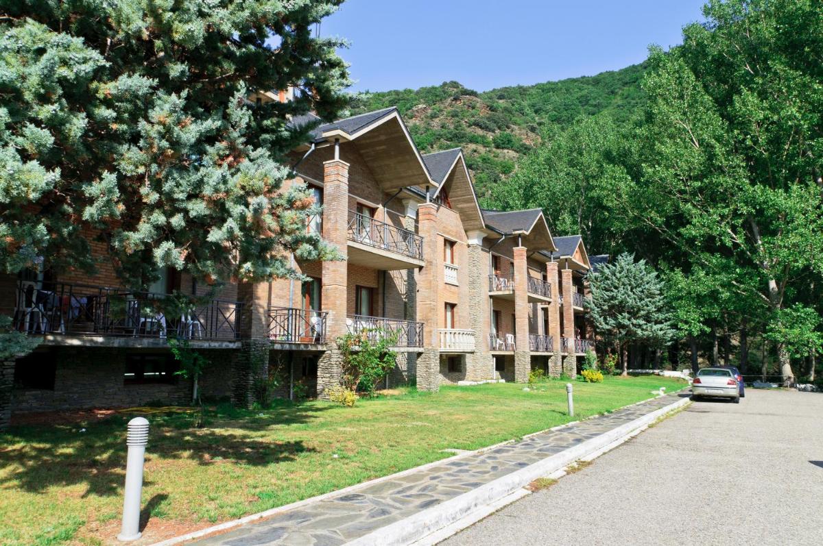 una gran casa de ladrillo con un coche aparcado delante de ella en Hotel Snö Condes del Pallars, en Rialp