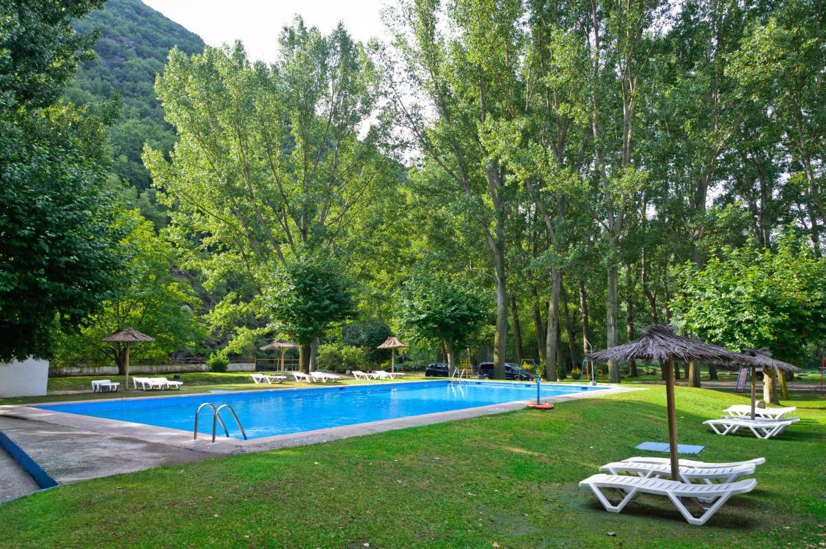 una piscina con dos sillas y una sombrilla en Hotel Snö Condes del Pallars, en Rialp