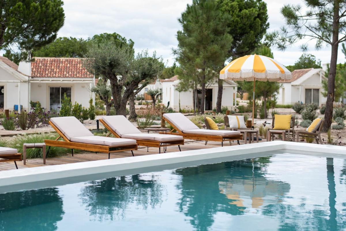 uma piscina com espreguiçadeiras e um guarda-sol em Independente Comporta na Comporta