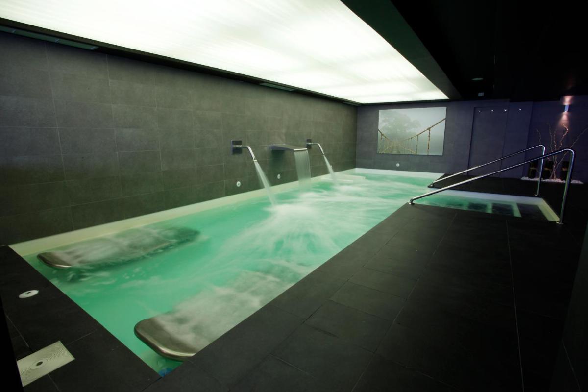y baño con bañera de agua azul. en Hotel Spa Sinagoga, en Hervás