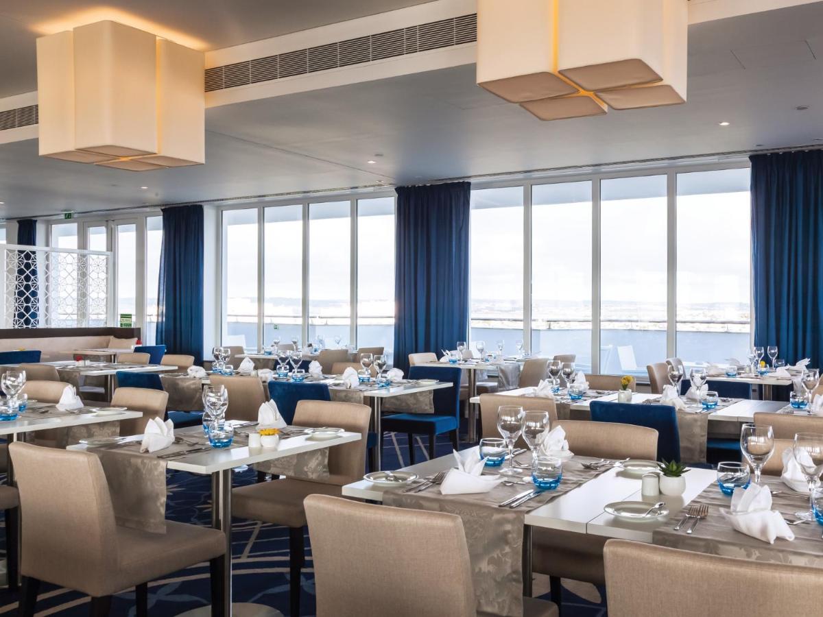 um restaurante com mesas e cadeiras e grandes janelas em MH Peniche em Peniche