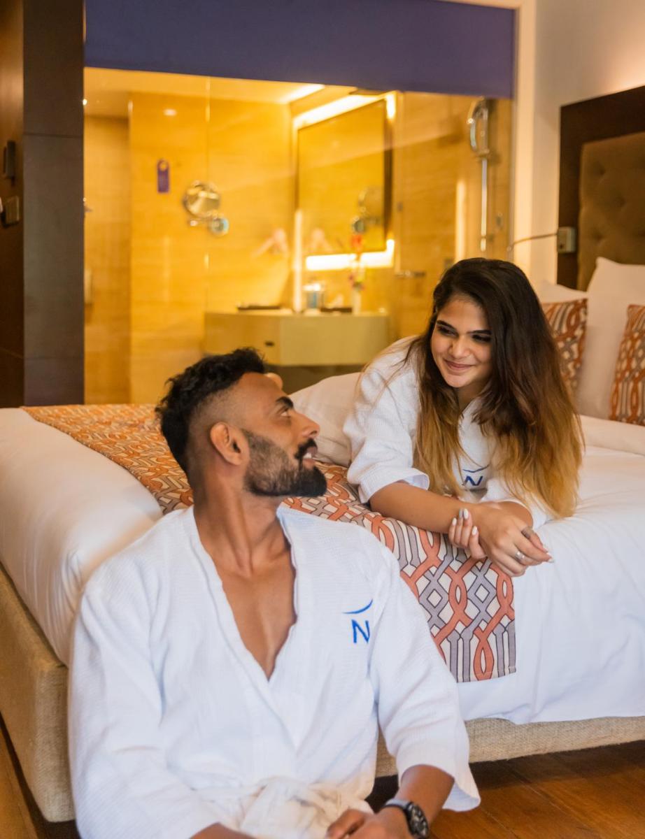 a man and a woman sitting on a bed at Novotel Goa Candolim in Candolim a man and a woman sitting on a bed at Novotel Goa Candolim in Candolim