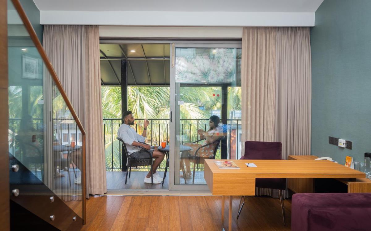 a living room with two people sitting on a balcony at Novotel Goa Candolim in Candolim a living room with two people sitting on a balcony at Novotel Goa Candolim in Candolim