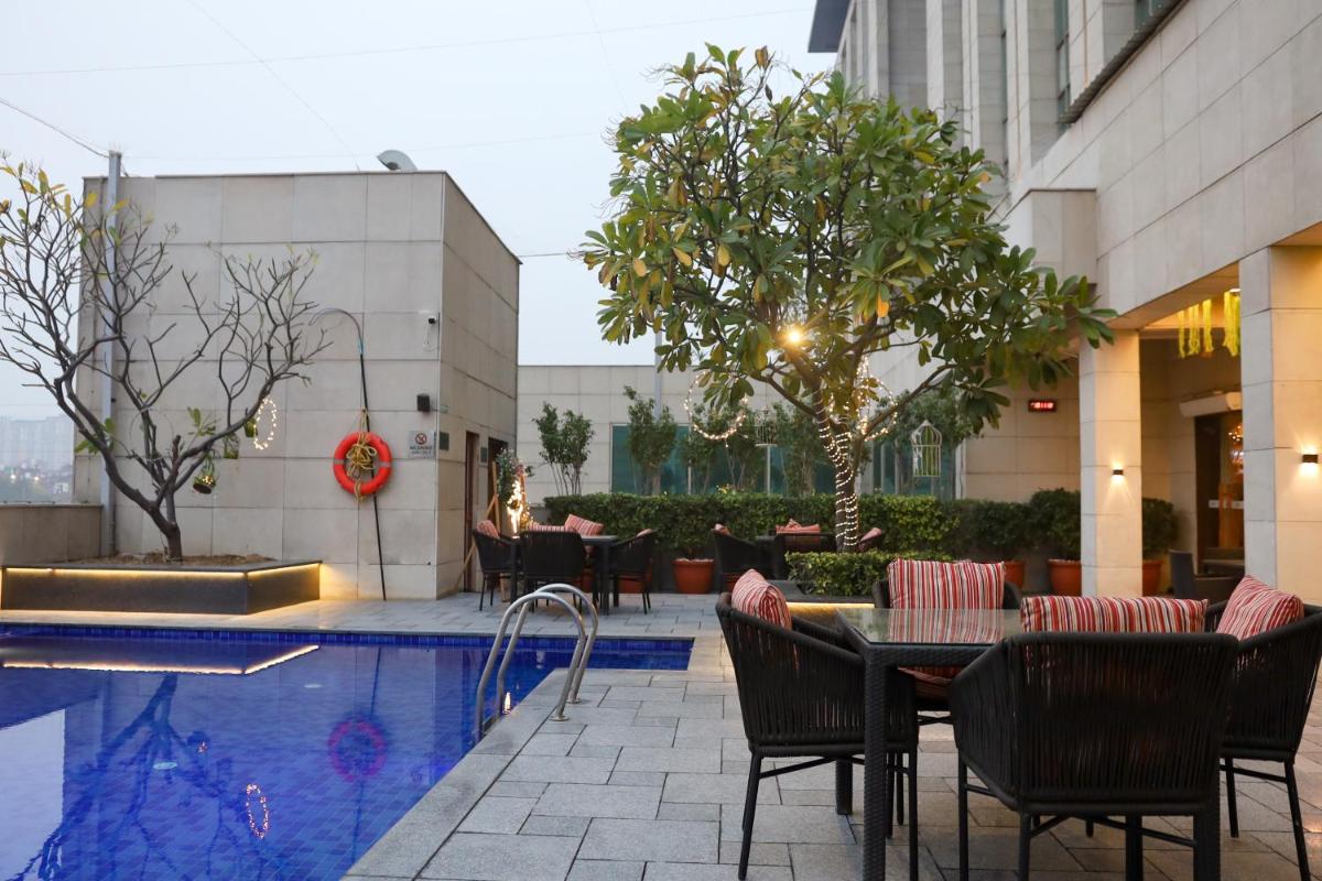 a hotel patio with a table and chairs next to a pool at Crowne Plaza New Delhi Okhla by IHG in New Delhi