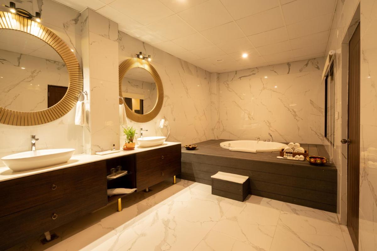 a bathroom with a sink and a tub and a mirror at The Orchid Shimla in Shimla